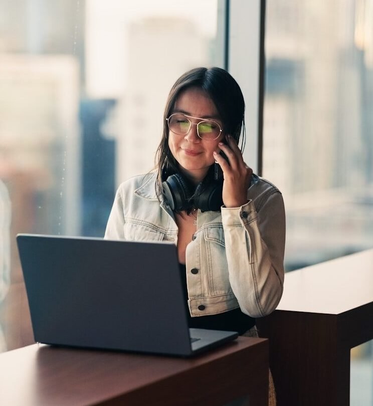 Woman talking on phone with laptop nearby
